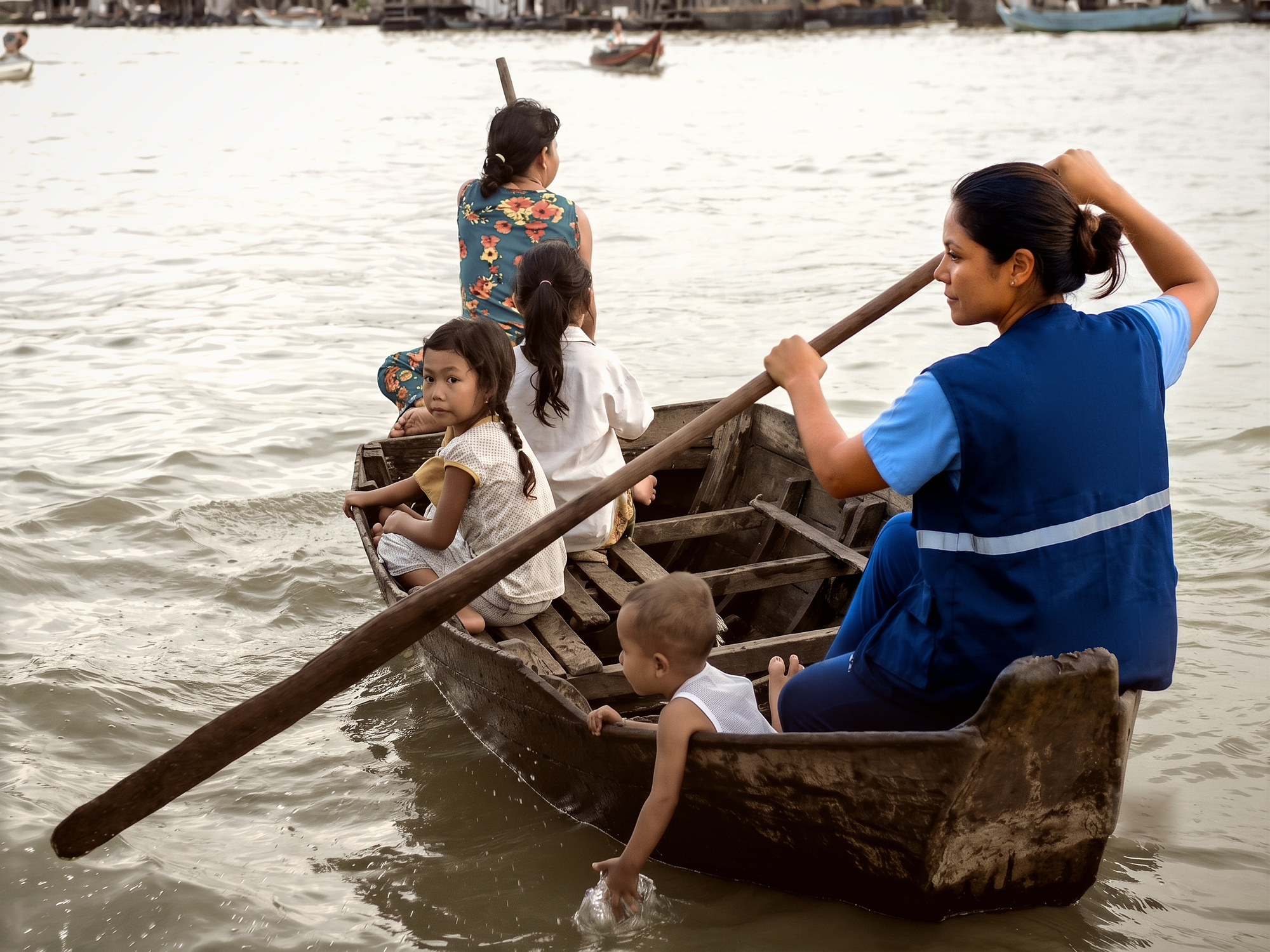 Agente de saúde rema uma canoa levando uma mãe e quatro crianças pelo rio