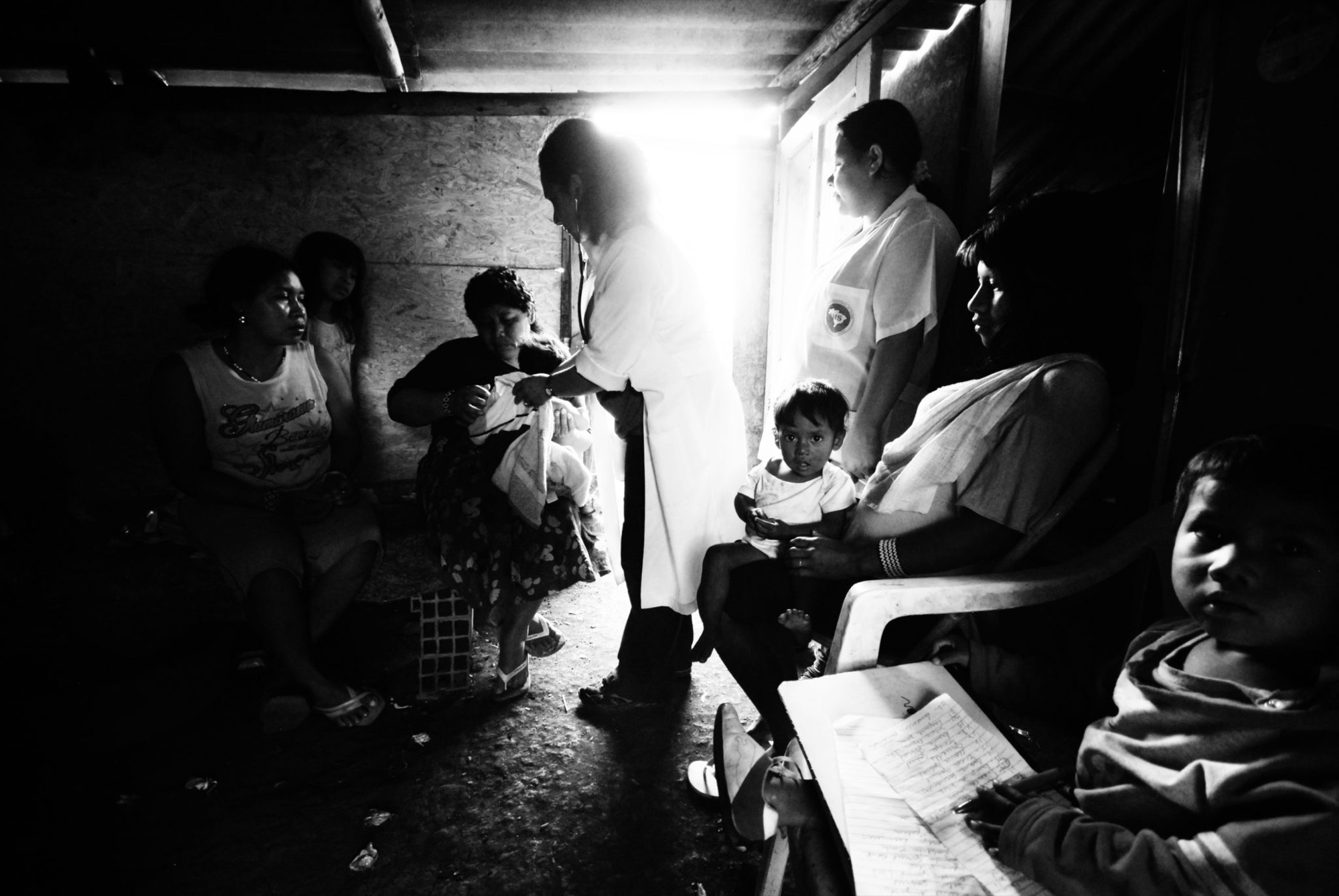 Equipe de saúde atendendo um grupo de pessoas dentro de um espaço improvisado